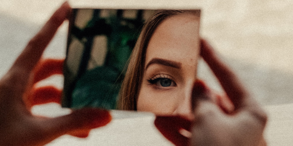 Particolare dalla locandina con il volto di una ragazza riflesso in uno specchio